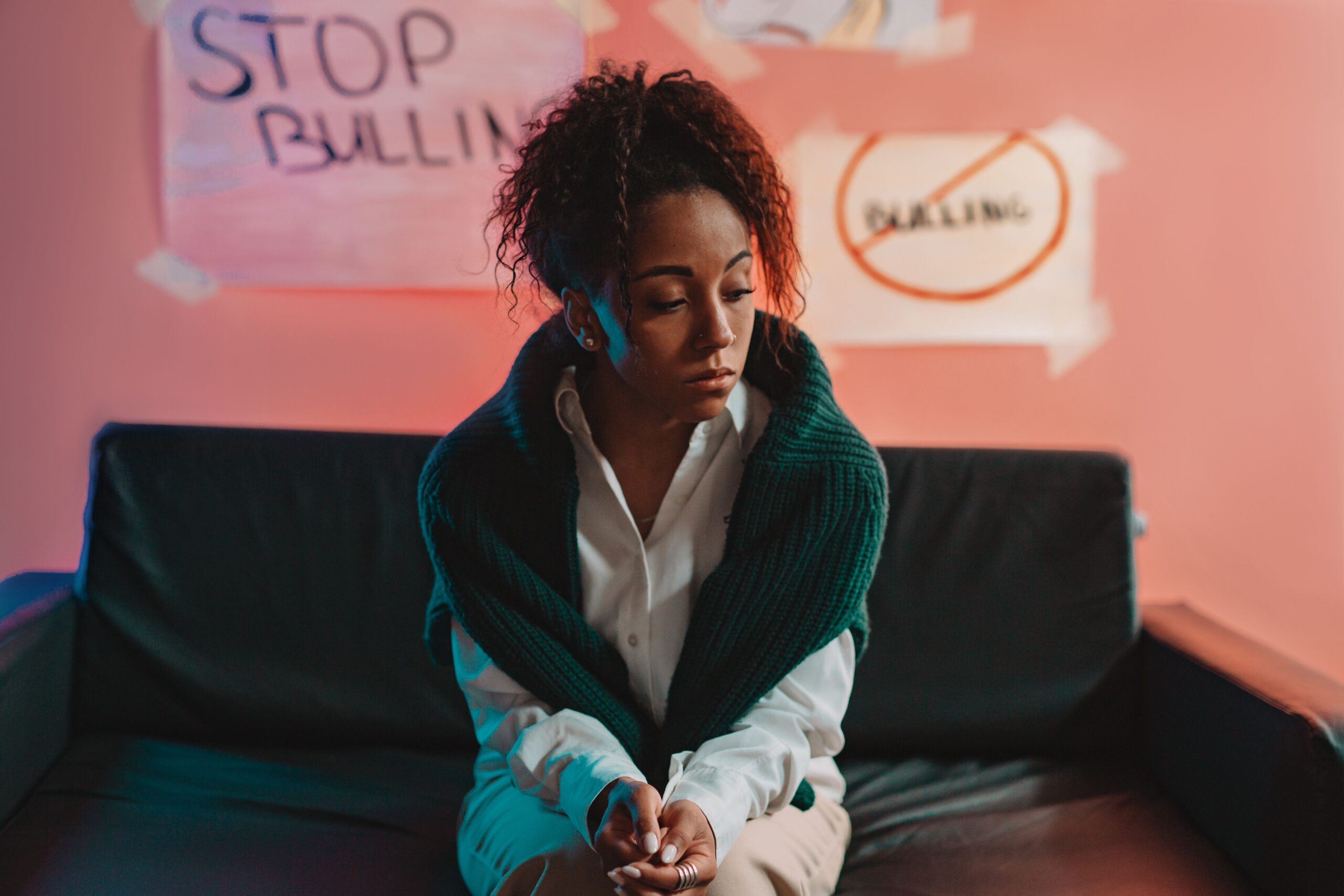 A thoughtful woman sitting indoors, highlighting bullying awareness.